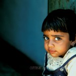 Small girl with huge eyes looks shyly into the camera