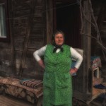 Romanian woman stands in front of her home