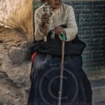 Tibetan woman sits and twirls her prayer wheel in Quinghai Provence China