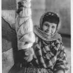 A Berber woman holds a swaddled baby upside down.