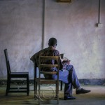A nicely dressed man reads in a sparsely furnished room at El Mina Castle