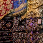 Embroidered and beaded silks hang in the Damascus Souk