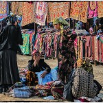 Uzbek women at the Urgut Market surrounded by hand embroidered Suzanis discuss the day's business.