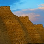 The massive walls of the ancient city of Bukhara glow in the evening light