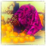 Large woman colorfully dressed stoops to pick up a melon in Bokhara market